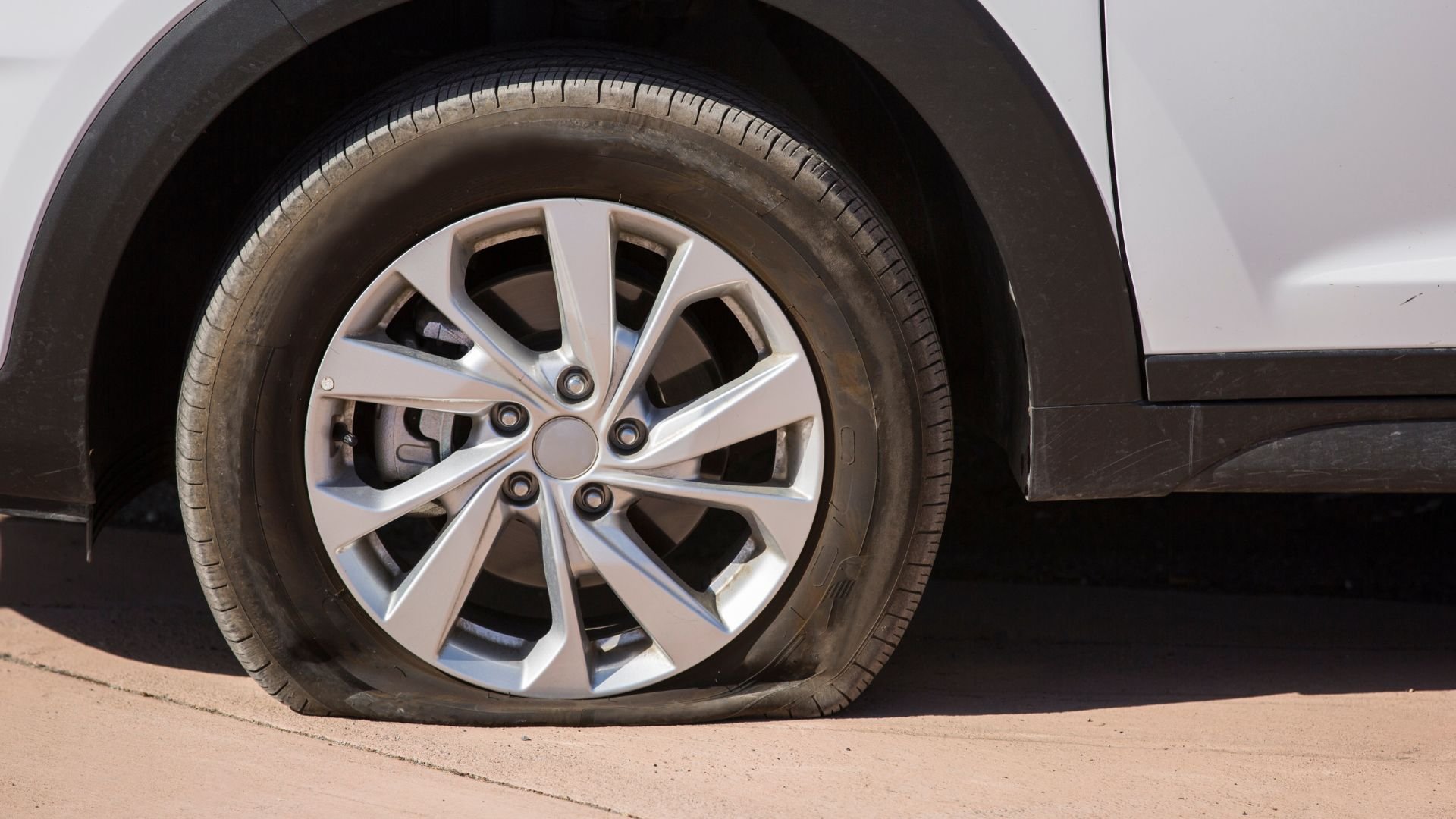 Flat tire on white car with silver wheel rim